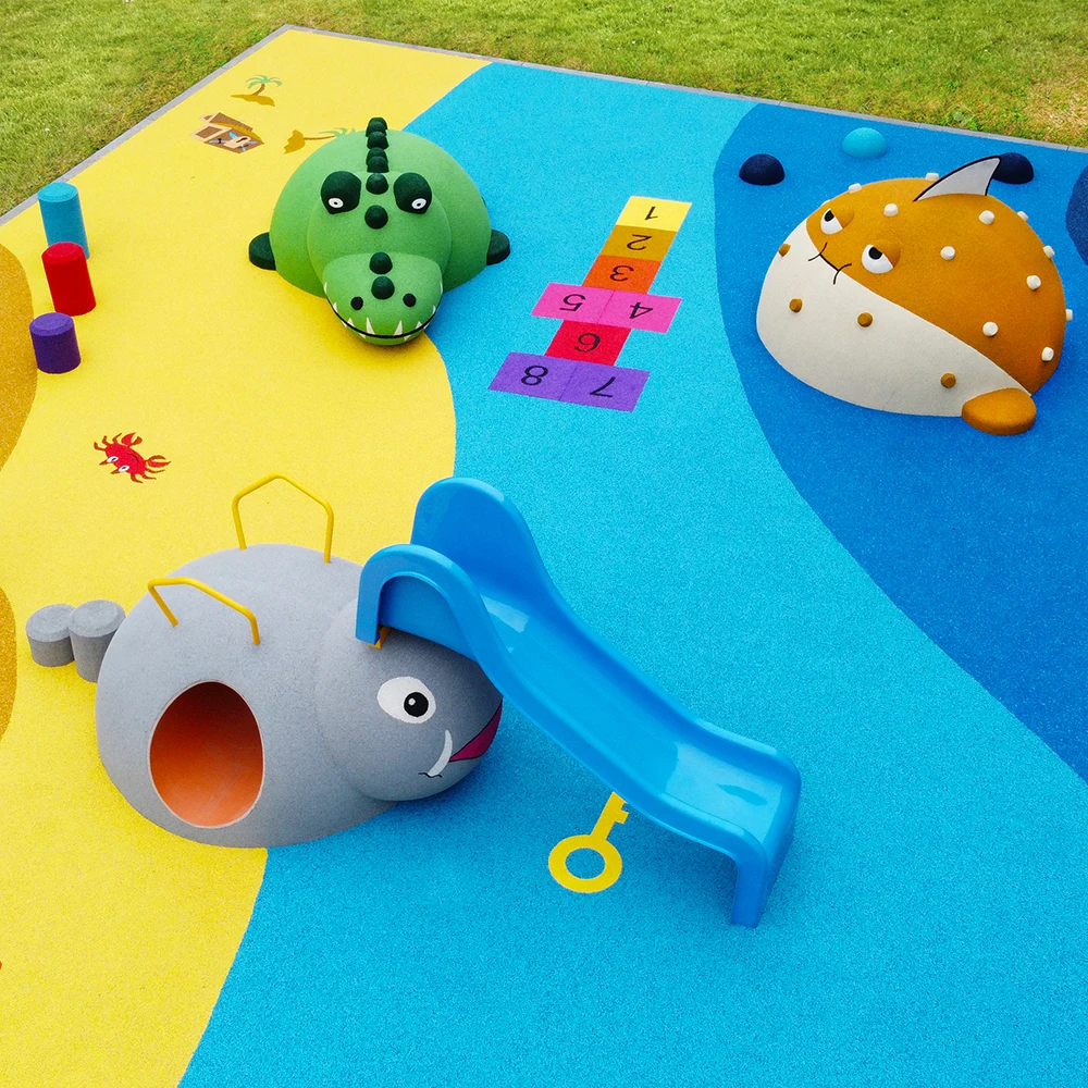 Colorful playground with animal-shaped play structures, a blue slide, hopscotch squares, and soft surface flooring featuring rubber surfacing applications for playgrounds. Grass borders the play area.